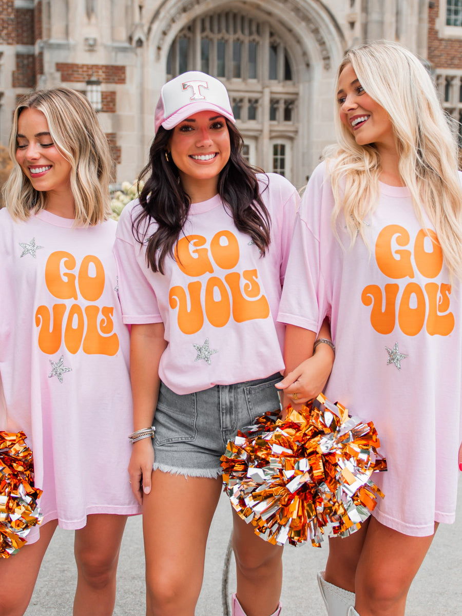Three women wearing GO VOLS pink tees