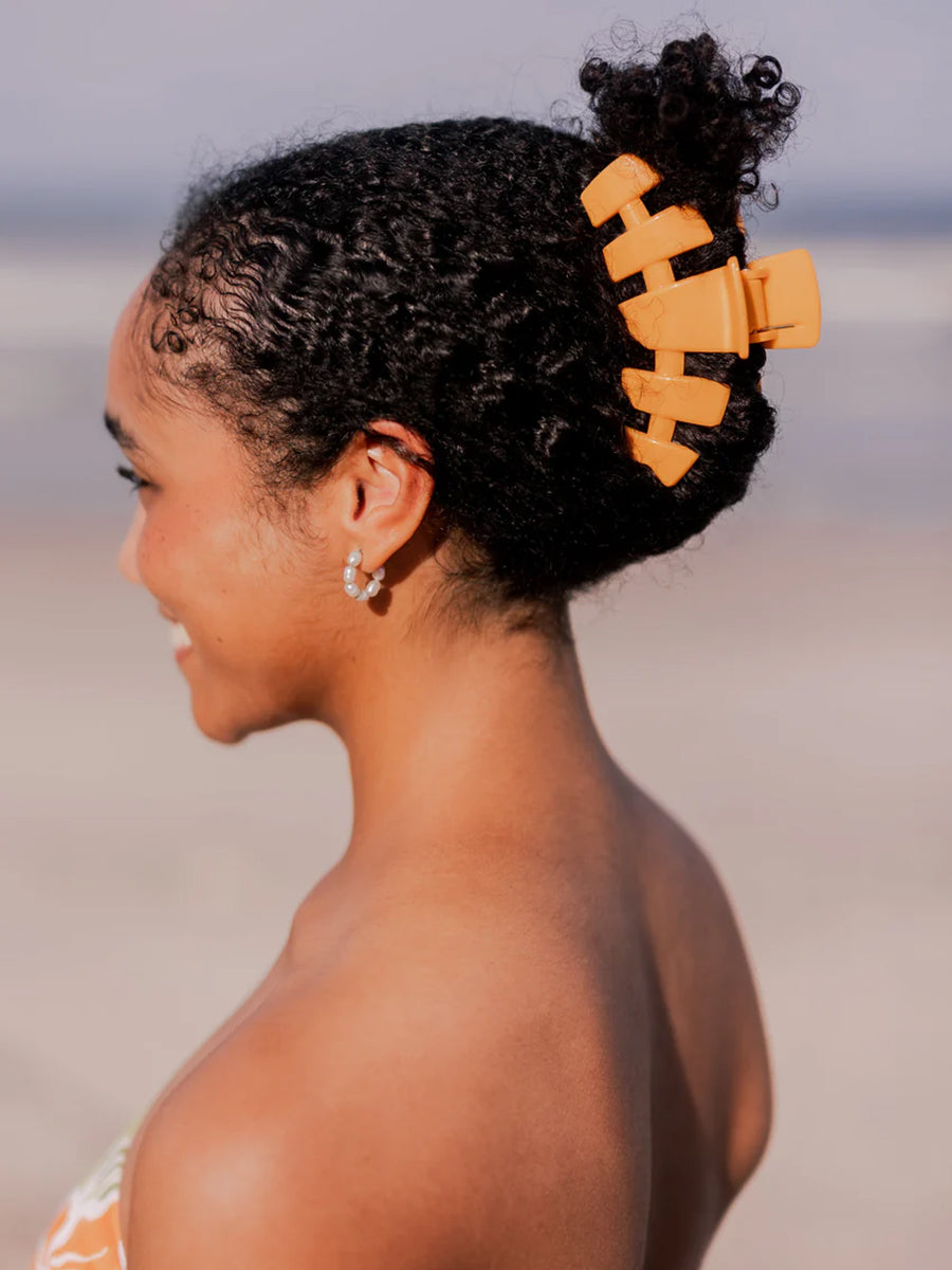 Large orange claw clip in hair