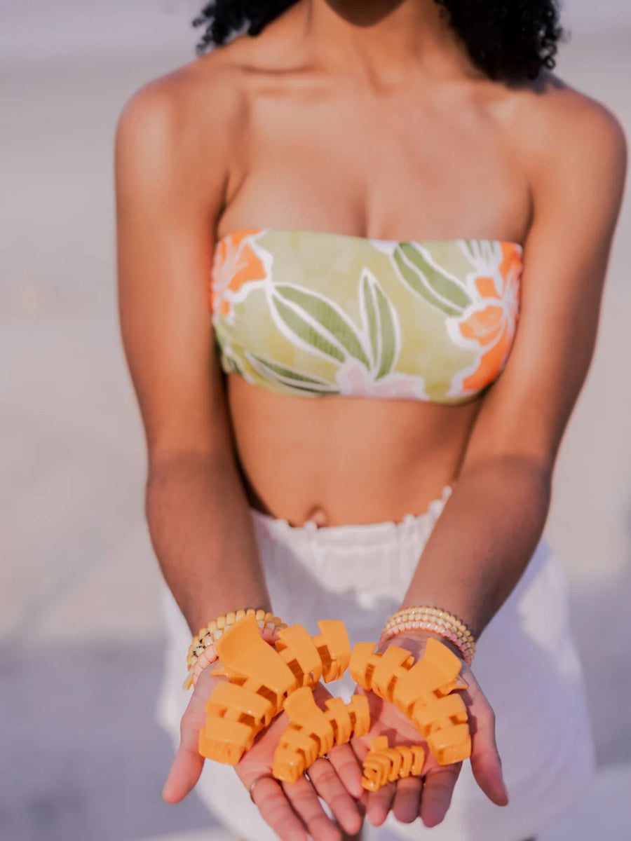 woman holding out 4 sizes of orange claw clips