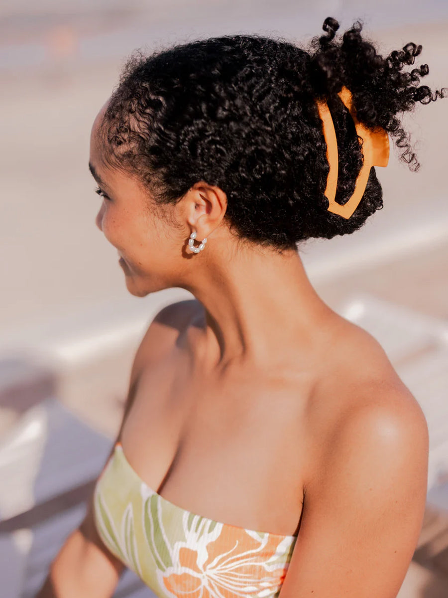 orange hair clip pulling back woman's hair