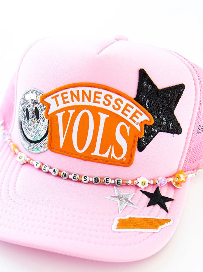 Pink hat with patches and a strand of beads that spells "Tennessee"