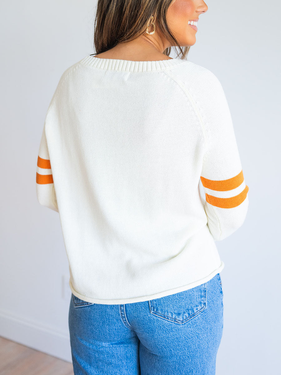 back of cream sweater with orange stripes on arms