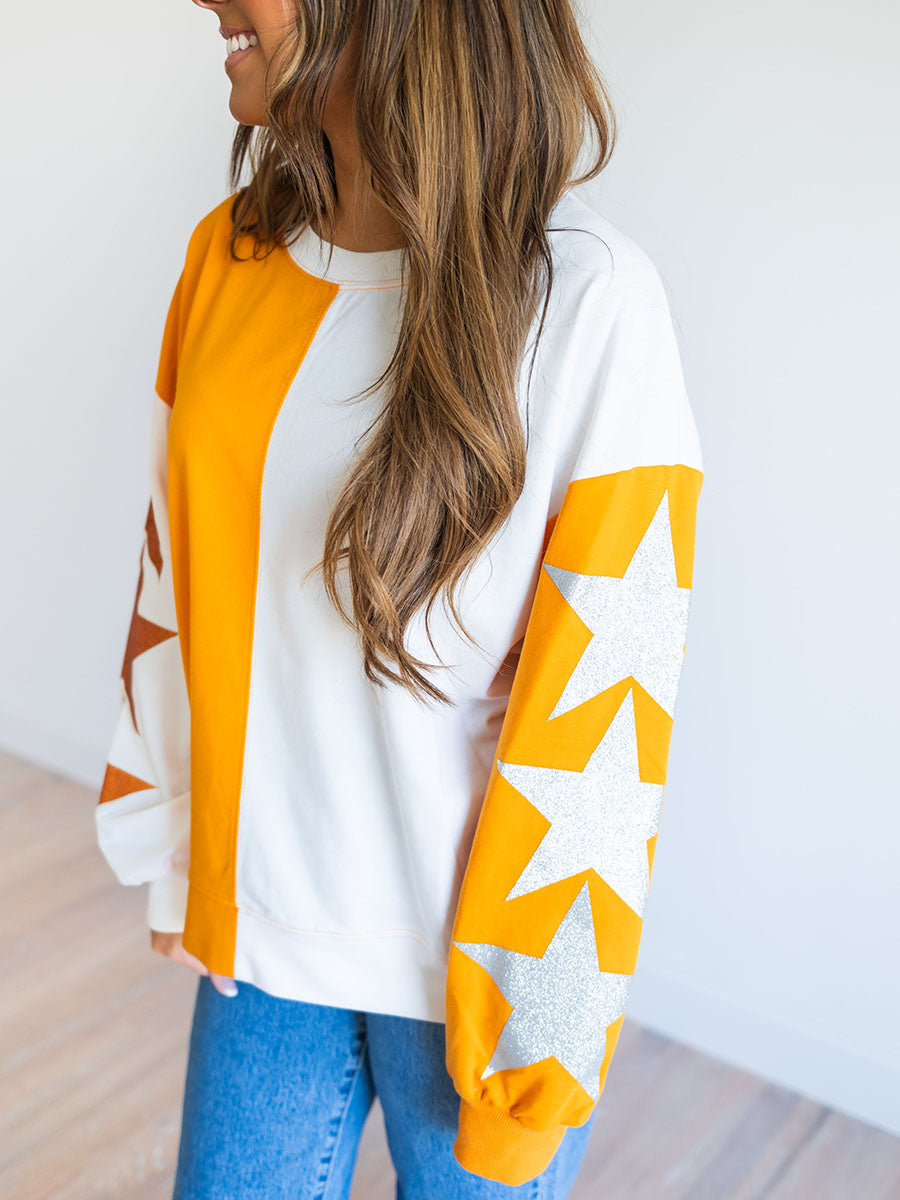 glitter stars on sleeves of orange and white sweatshirt