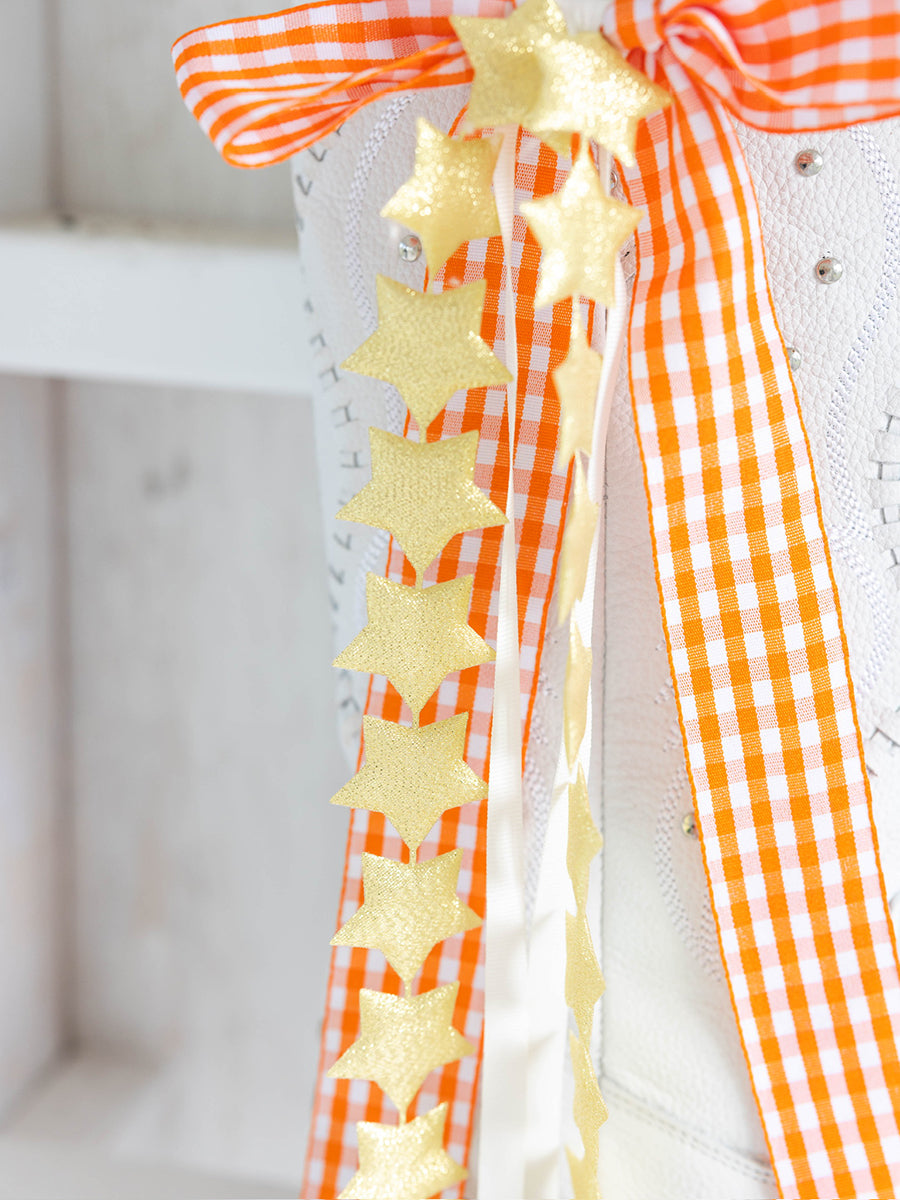 Decorative bow with gold stars and orange checkered ribbon
